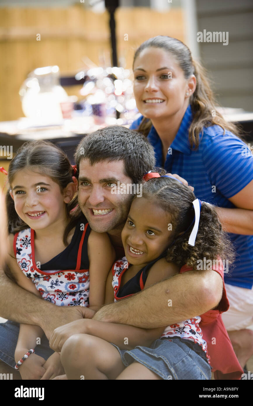 Mann Eng Umarmt Zwei Junge Mädchen Mit Frau Im Hintergrund Kichern Stockfotografie Alamy 