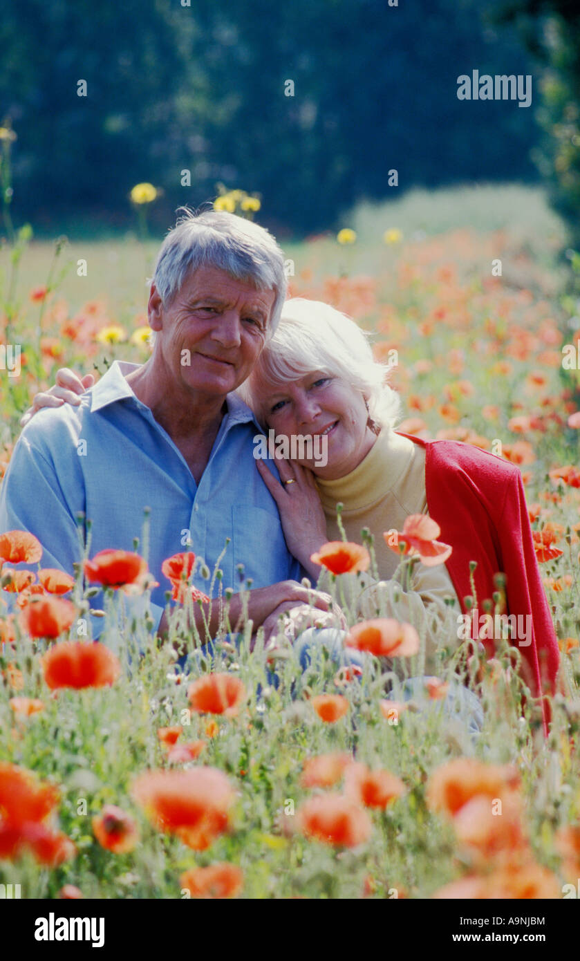 Porträt liebevolle Reife Brautpaar sitzen im Mohnfeld Stockfoto