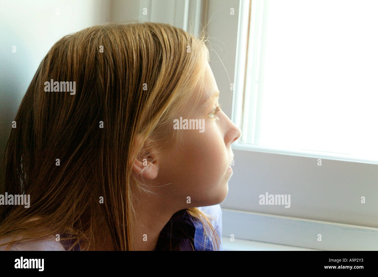 Junges Mädchen schaut aus Fenster Stockfoto