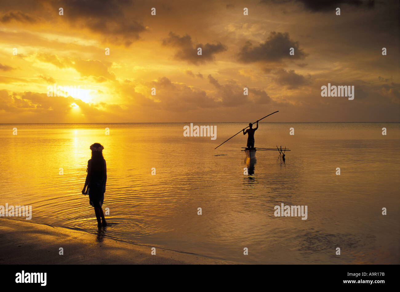 Ausleger-Kanu in Aitutaki Lagune bei Sonnenuntergang mit polynesischen Mädchen in seichtem Gewässer Cookinseln Südsee Stockfoto
