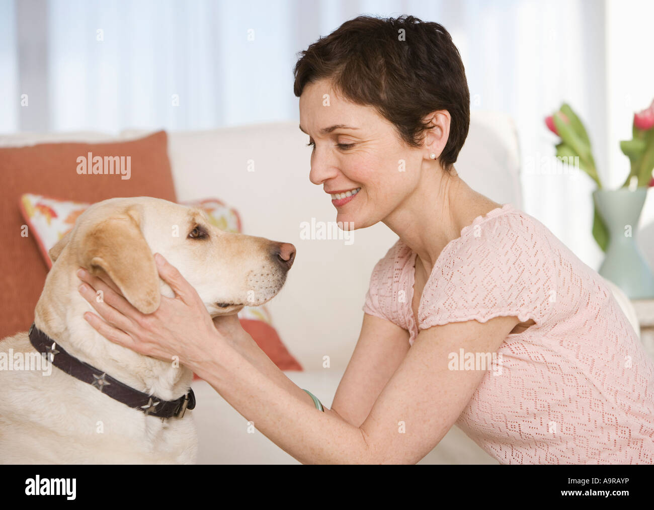 Frau Petting Hund im Wohnzimmer Stockfoto