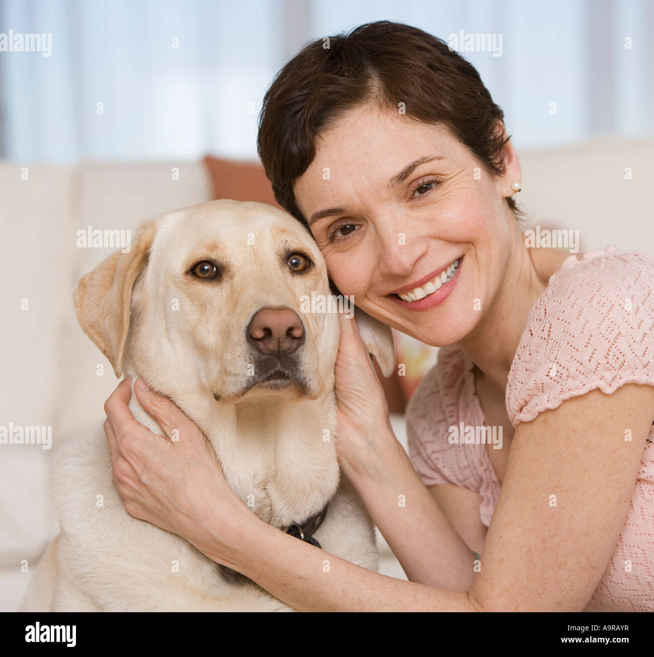 Frau umarmt Hund im Wohnzimmer Stockfoto