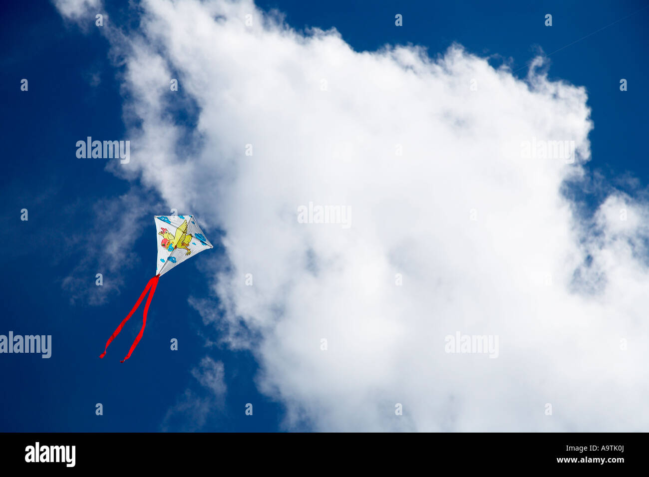 Drachen fliegen gegen blauen Himmel mit flauschigen Wolken Stockfoto