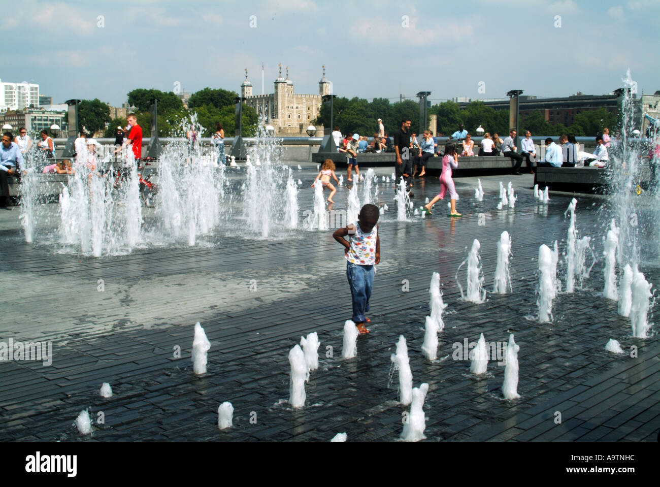 Weitere Sanierungsgebiete am Flussufer der Themse mit Kindern und Familien, die die Brunnen genießen, darunter der Tower of London jenseits von England Großbritannien Stockfoto