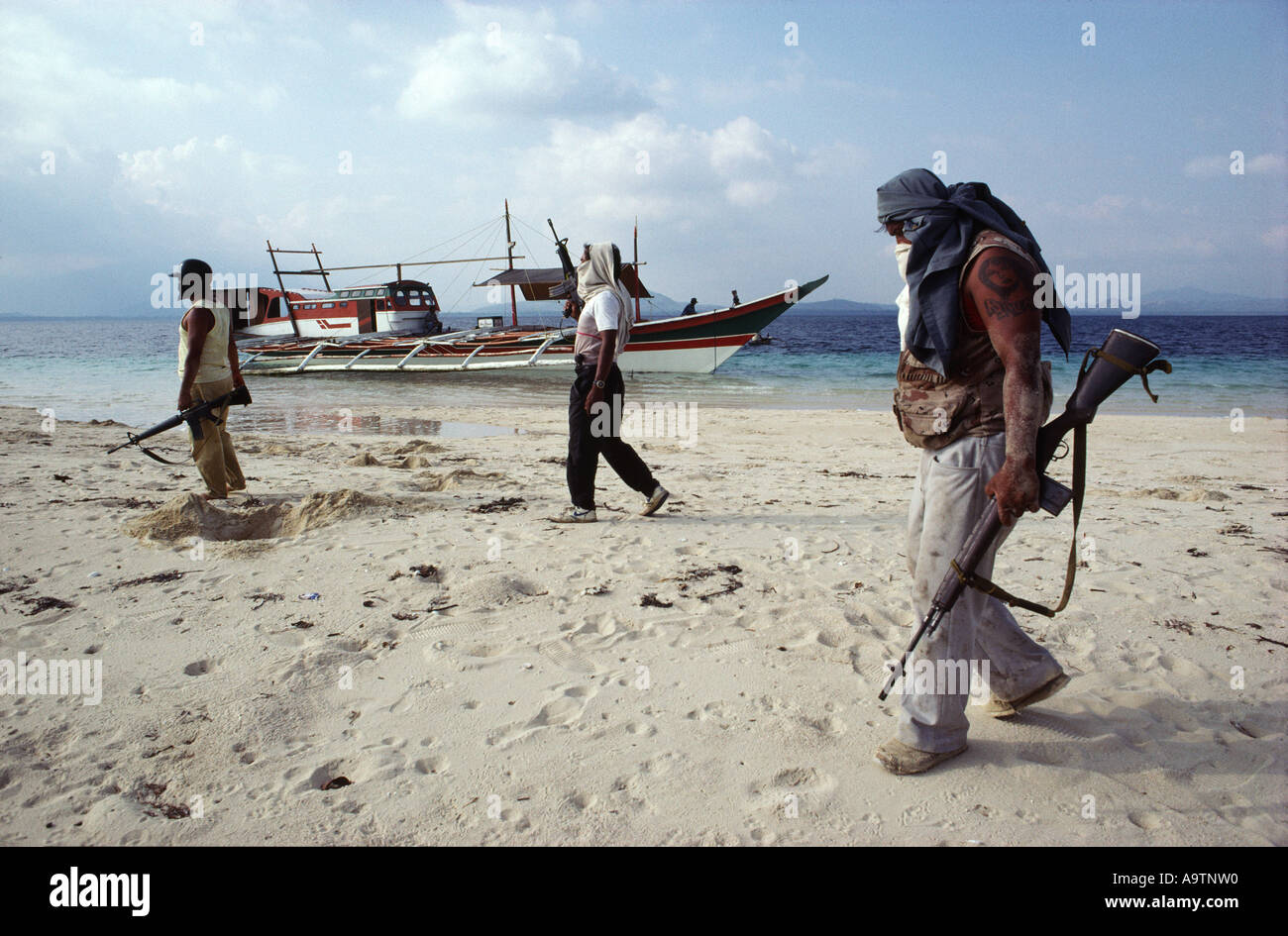 Die Piratencrew Wandern entlang dem Strand von einer flachen Sandbank, ihr Boot im Hintergrund. Stockfoto