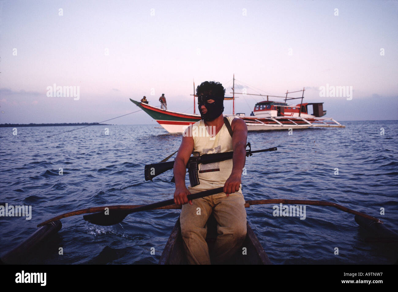 Piraten-Tony in das kleine Boot mit dem UN-markierten Piraten Schiff hinter Stockfoto