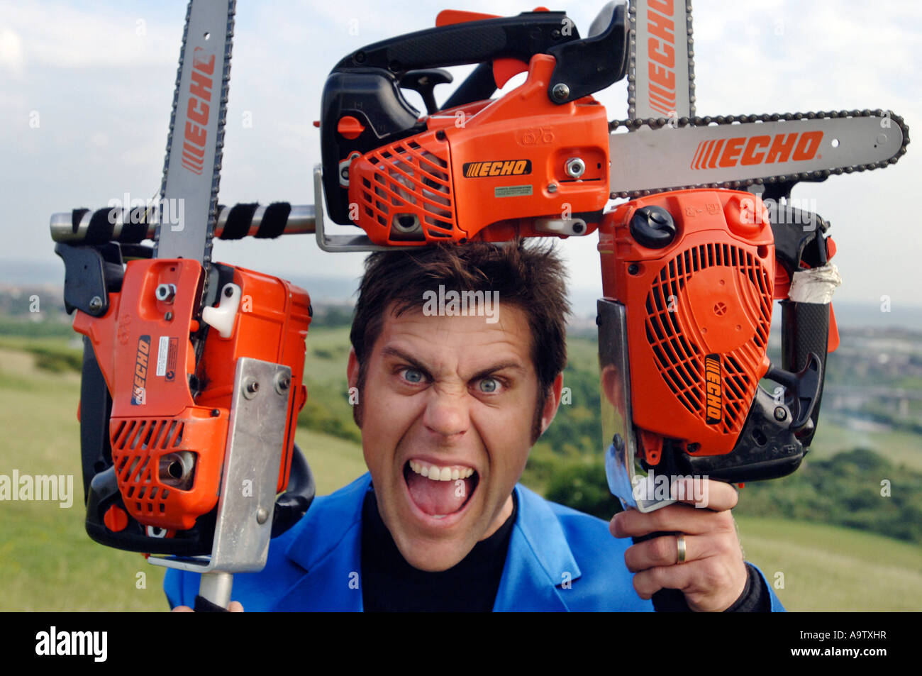 Junger Mann mit harten Gesicht umrahmt von drei orange Kettensägen Stockfoto