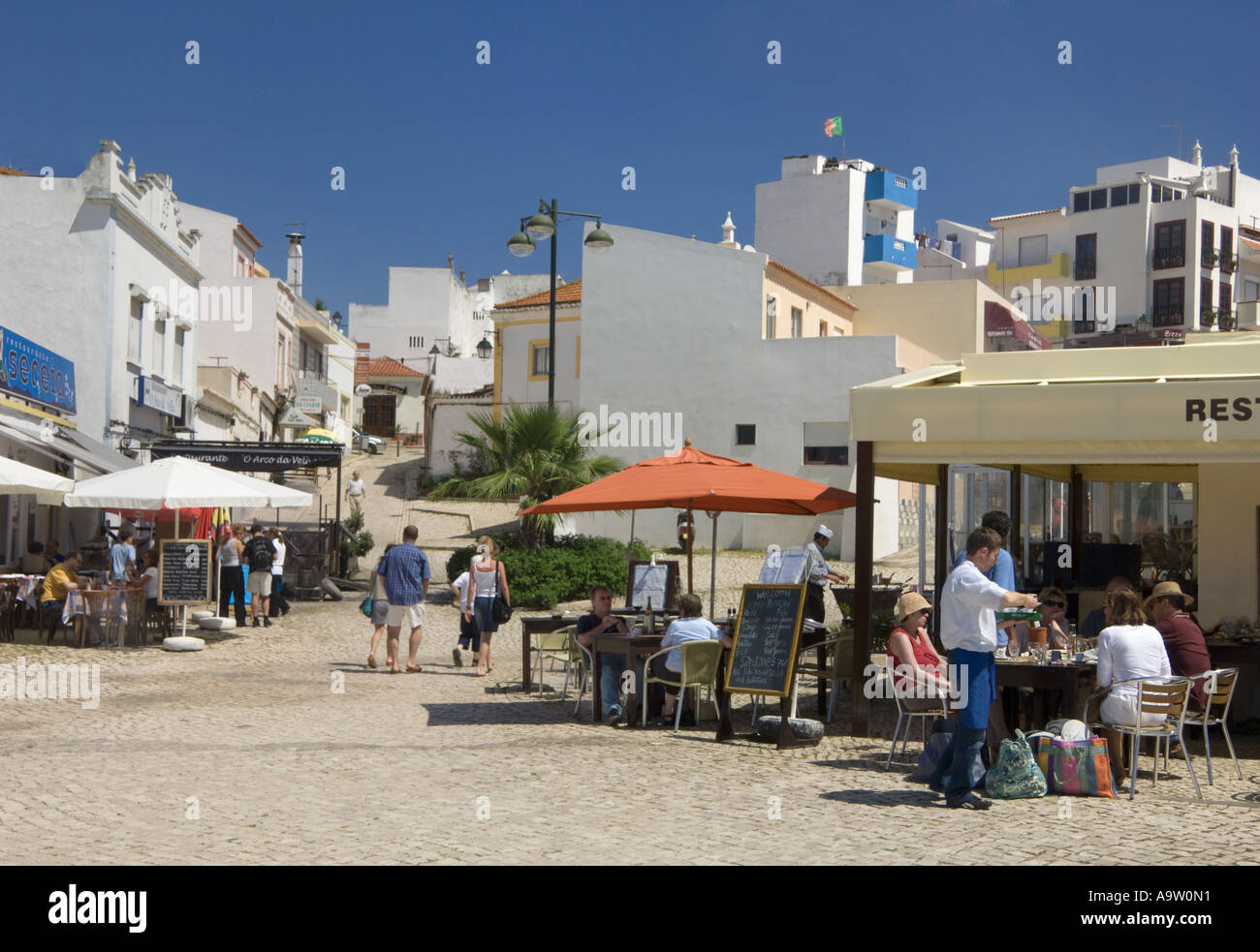 Straßenszene in Alvor, Algarve, Portugal, mit Fisch-Restaurants entlang der Straße Stockfoto
