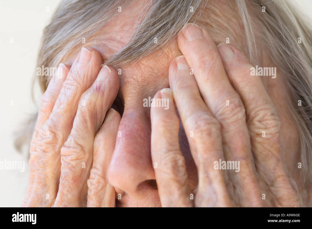 arthritischen faltige Hände der alten Frau Gesicht versteckt Stockfoto
