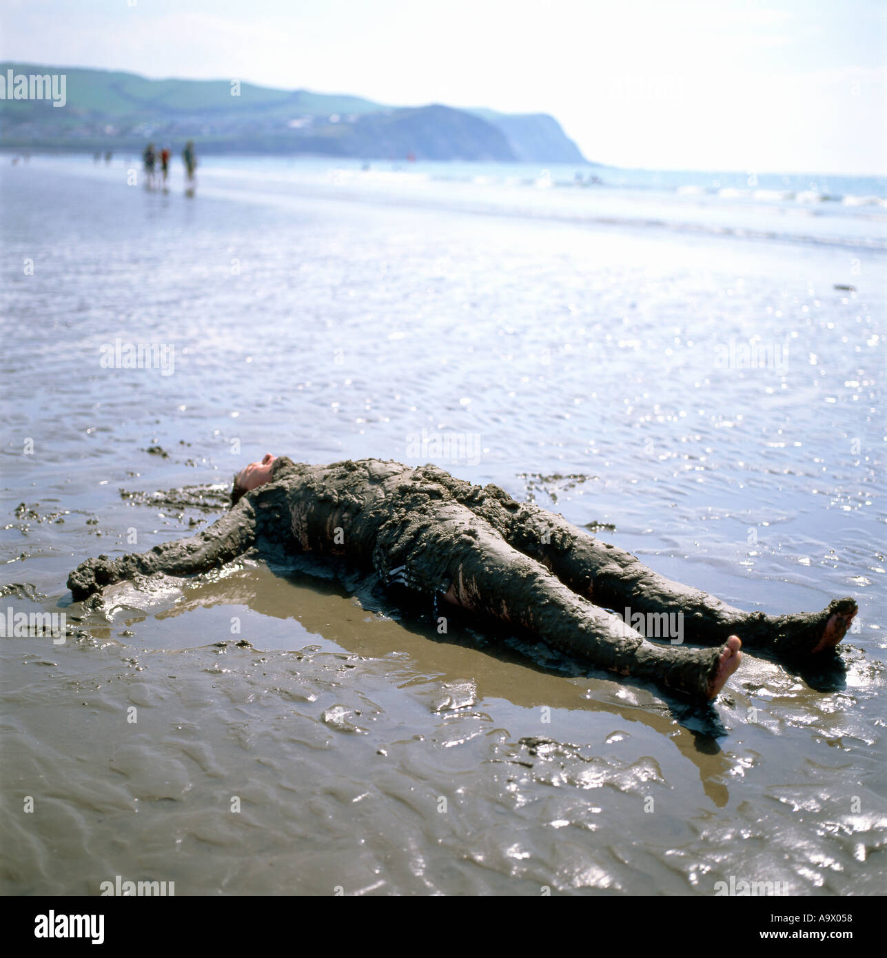 Ein Mann entspannt liegen am Ufer des Meeres bedeckt im Sand am Strand von Borth Ceredigion Wales UK Stockfoto
