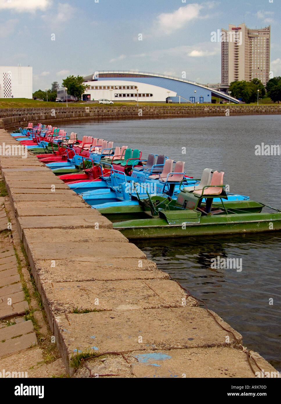 Reihe der farbigen Tretboote am künstlichen See mit Minsk Sport Palast- und Touristenhotel im Hintergrund, Minsk, Weißrussland Stockfoto