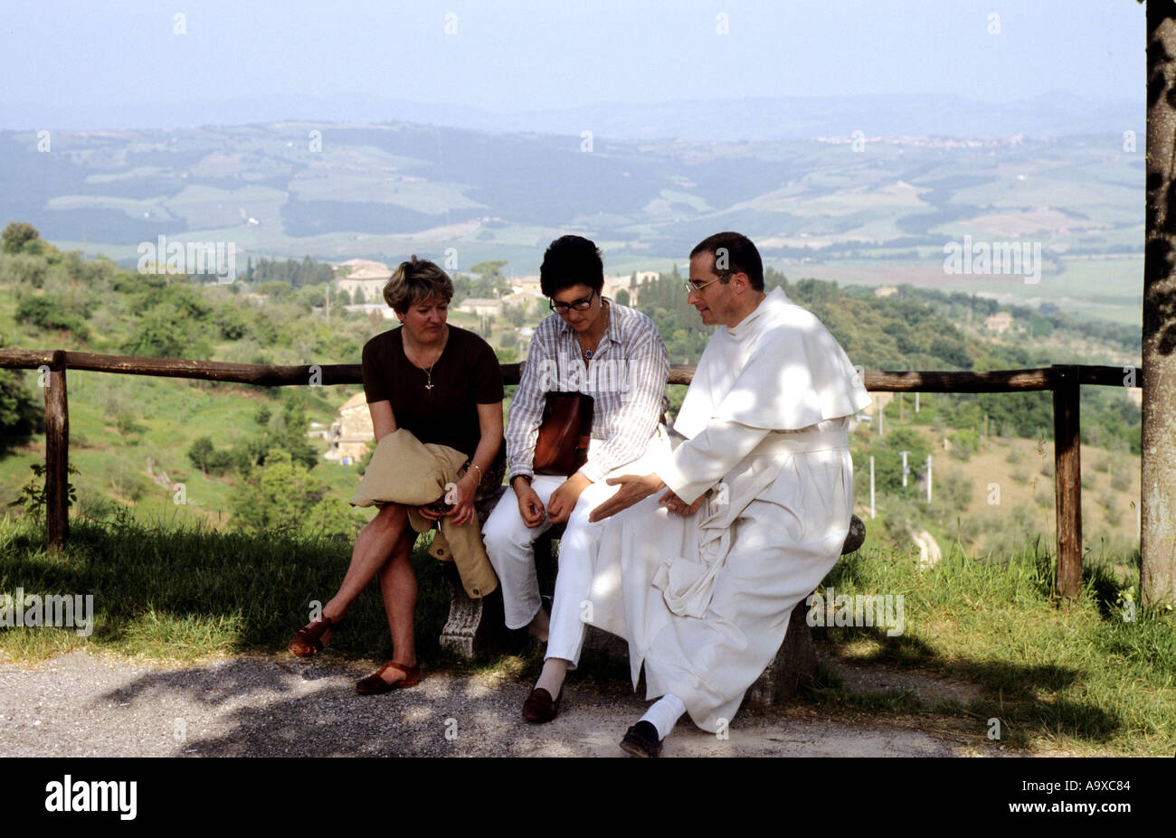 Eine weiß gekleidete Mönch aus St. Antimo in Converation mit zwei Frauen Toskana Italien Stockfoto