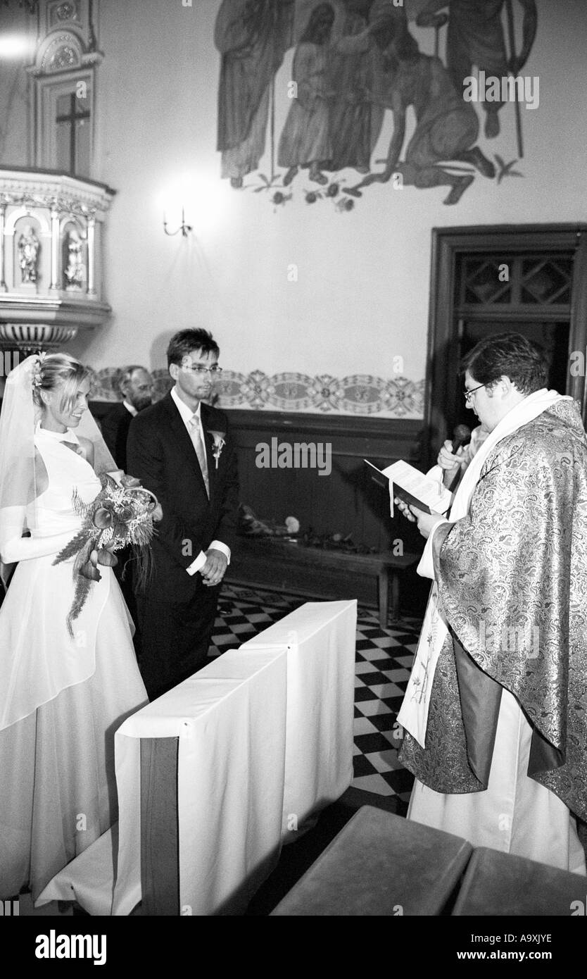 Polen, Lodz, Braut und Bräutigam mit Pfarrer in der Kirche, Seitenansicht (B&W) Stockfoto