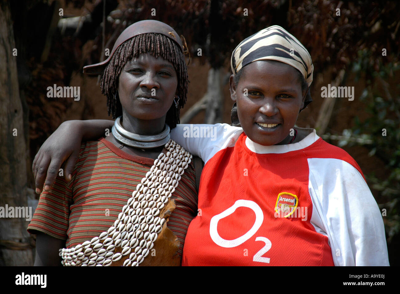 Zwei Freundinnen eine mit traditionellen Kauri Muscheln Schmuck gekleidet andererseits in einem modernen O2 T-shirt Markt Keyafer Äthiopien Stockfoto