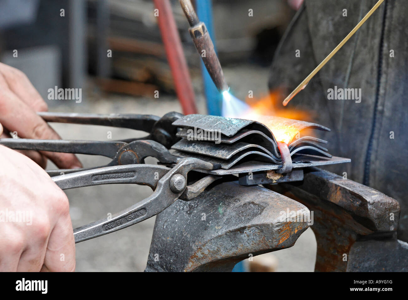 Junge Schlosser auszubildende Schweißen ein Werkstück aus Metall, Stockfoto