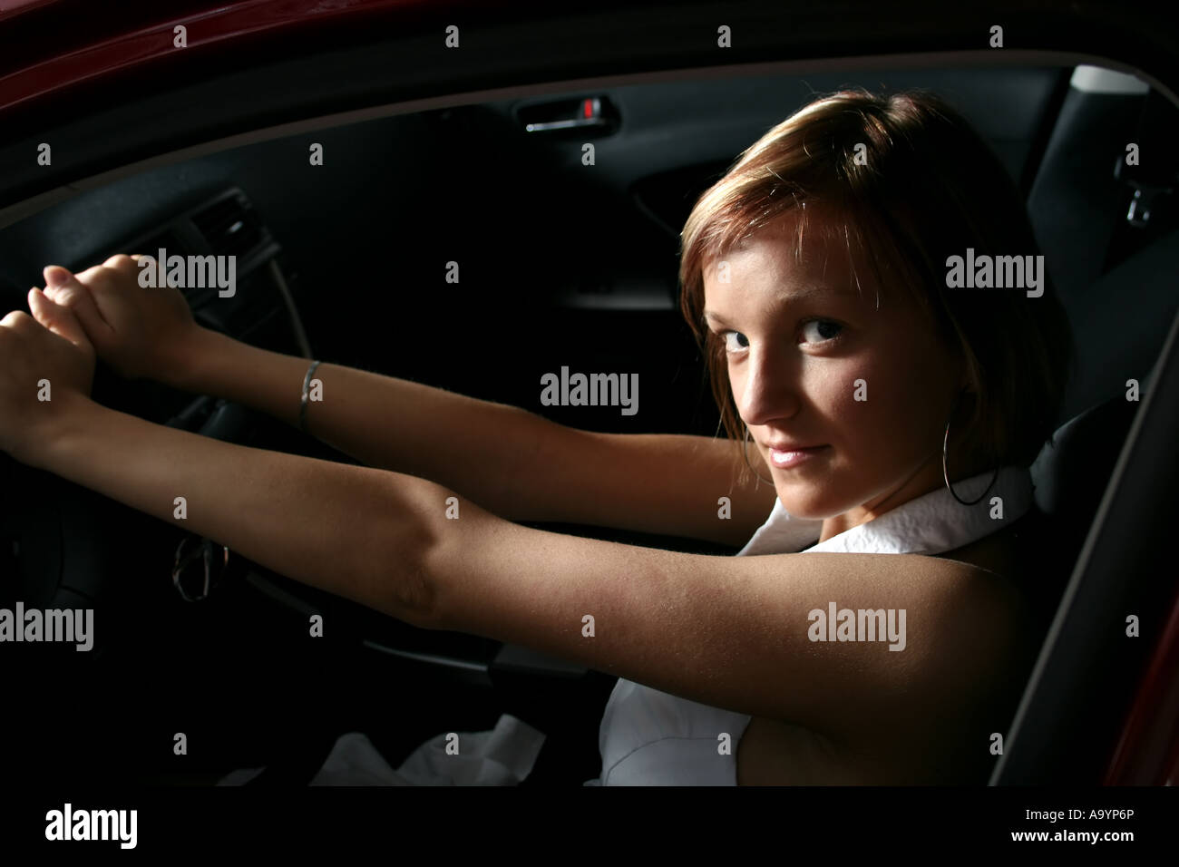 Junge Frau, die selbstbewusst in einem Auto sitzt, das Lenkrad mit einem subtilen Lächeln hält und Unabhängigkeit und einen modernen Lebensstil zum Ausdruck bringt. Stockfoto