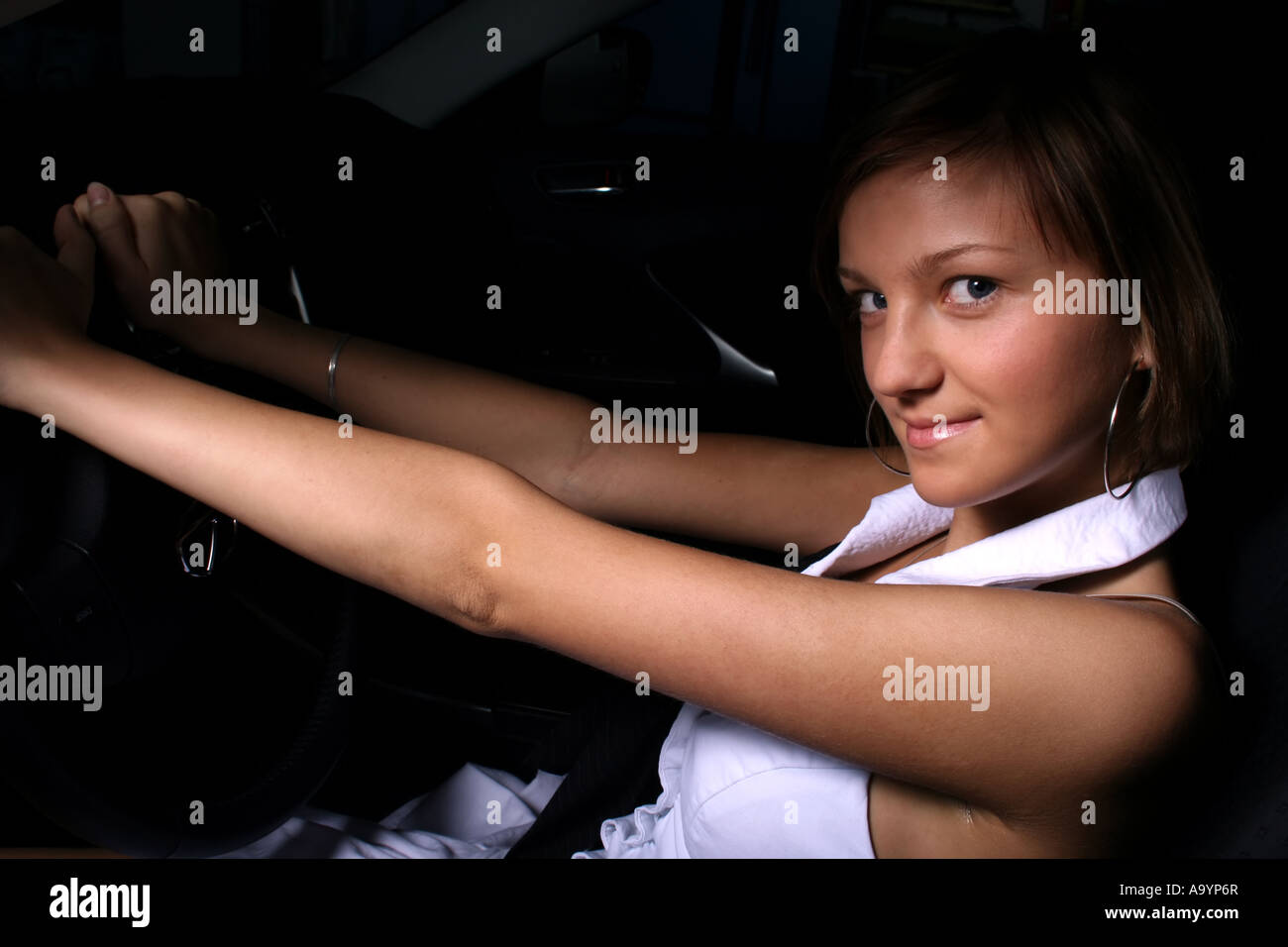Junge Frau, die selbstbewusst in einem Auto sitzt, das Lenkrad mit einem subtilen Lächeln hält und Unabhängigkeit und einen modernen Lebensstil zum Ausdruck bringt. Stockfoto