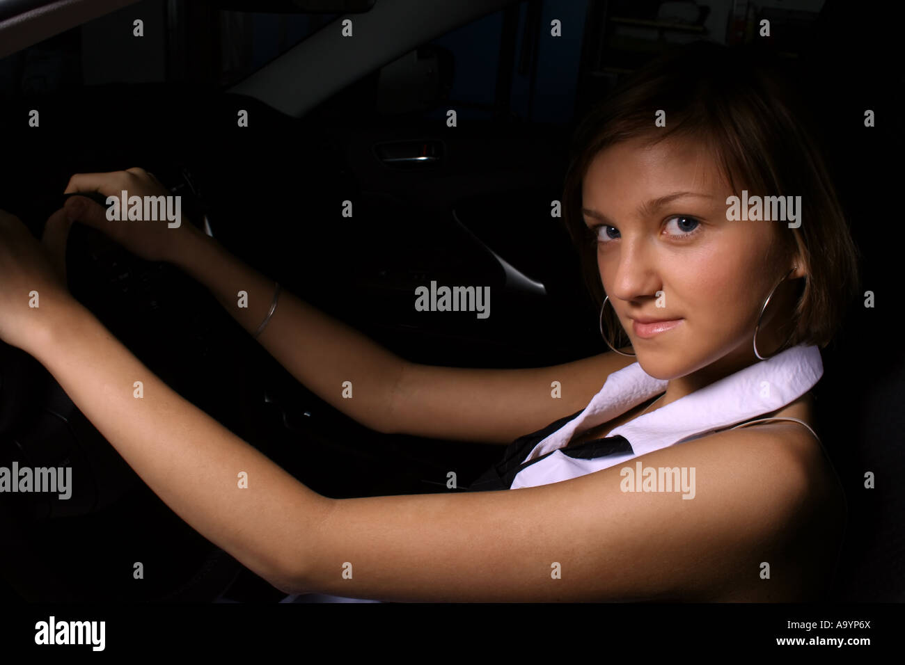 Junge Frau, die selbstbewusst in einem Auto sitzt, das Lenkrad mit einem subtilen Lächeln hält und Unabhängigkeit und einen modernen Lebensstil zum Ausdruck bringt. Stockfoto
