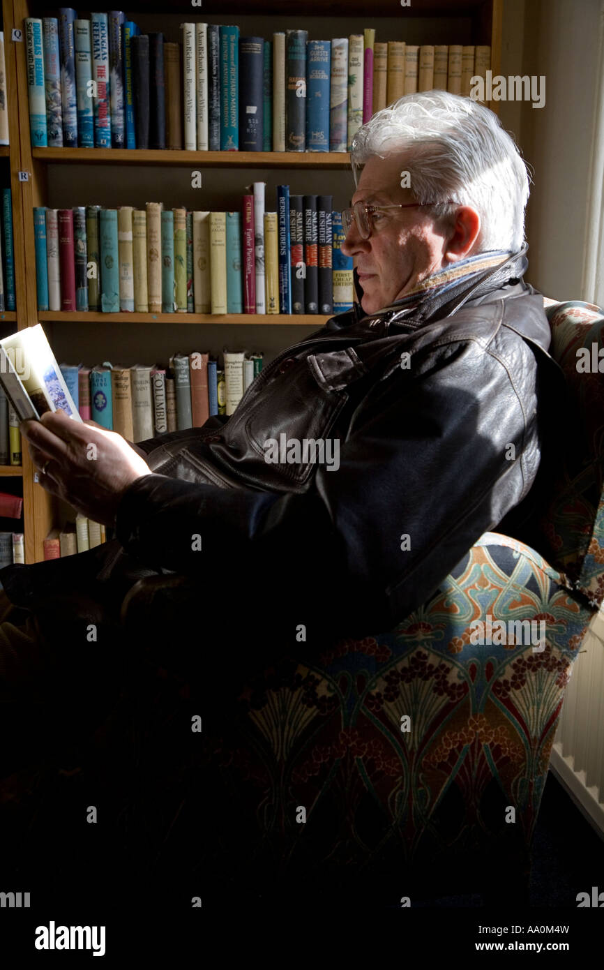 Älterer Mann sitzt in einem Sessel in einer Buchhandlung in Hay on Wye England lesen Stockfoto