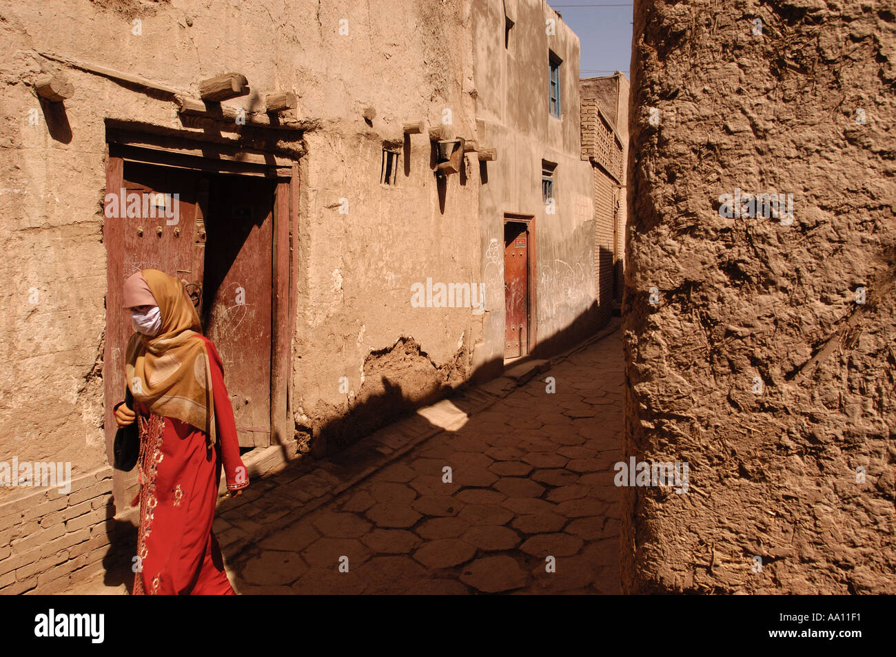 Eine Uyghur Frau kommt in einer Gasse in der Altstadt von Kashgar Xinjiang Provinz China Stockfoto