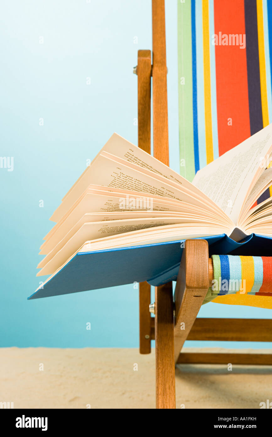 Offenes Buch im Liegestuhl Stockfoto