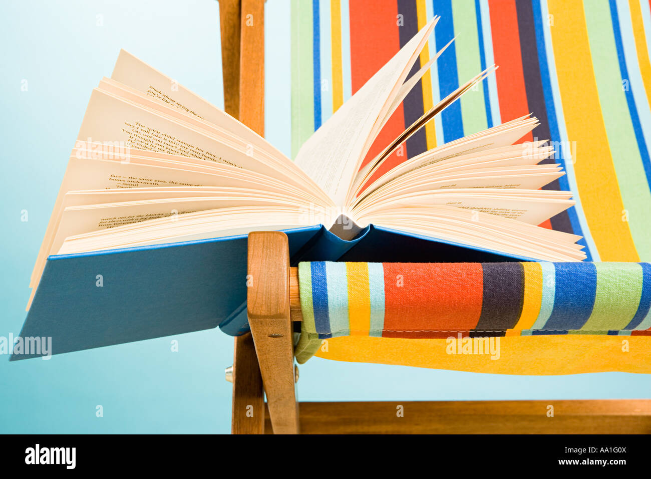 Offenes Buch im Liegestuhl Stockfoto