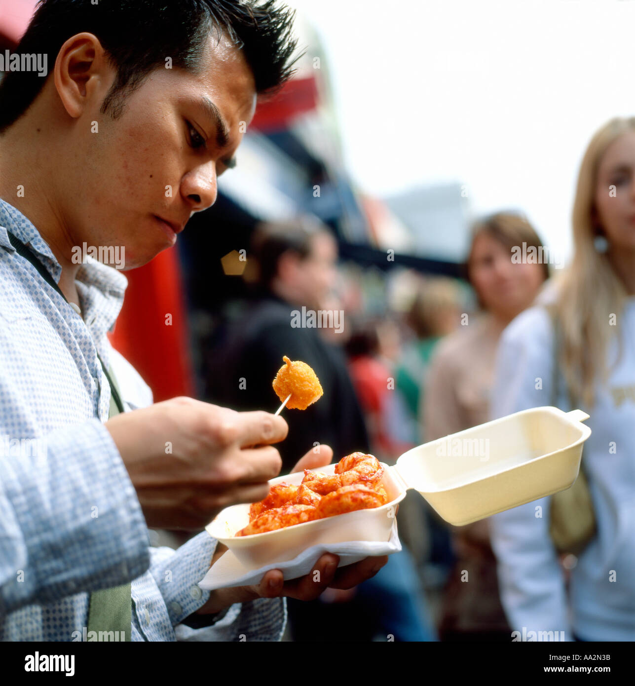 Ein Mann isst Fast-Food in Portobello Road Market London Stockfoto