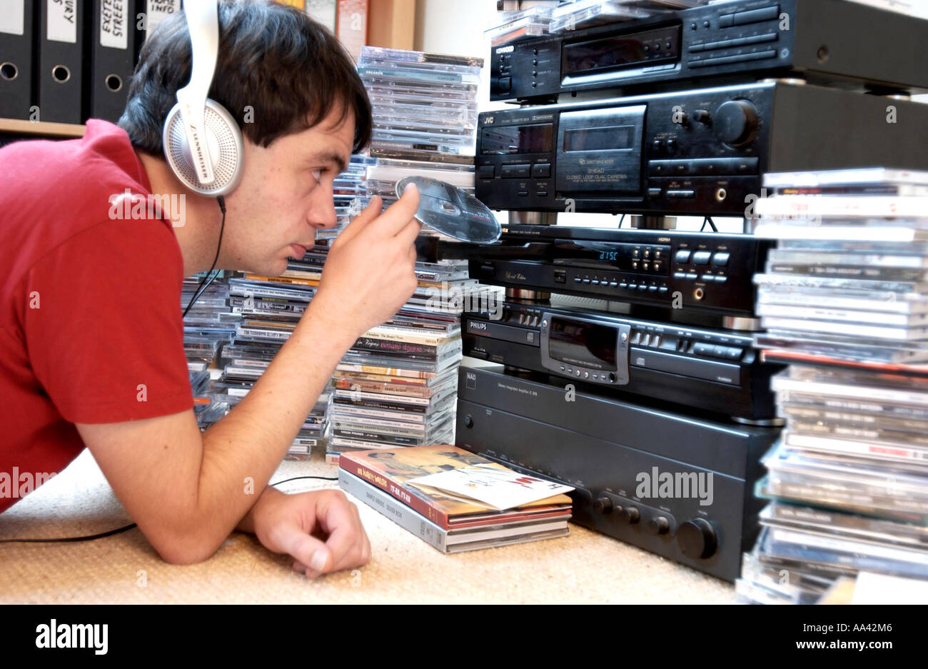 Junger Mann im Laden einer cd in ein Stereo-System mit Haufen von Musik-Alben um ihn herum Kopfhörer Stockfoto