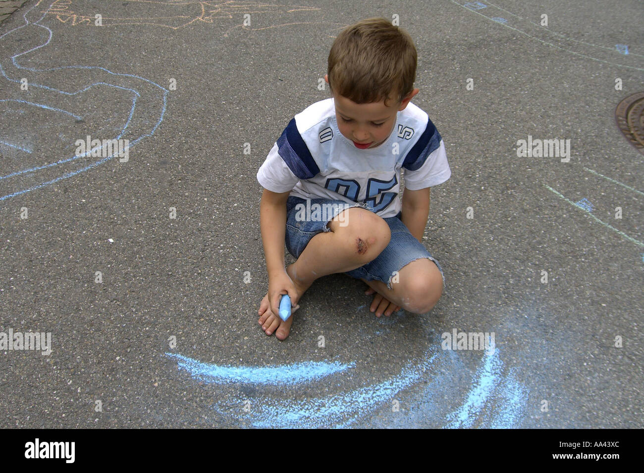 Kind ist auf der Straße mit blauer Kreide zeichnen Stockfotografie - Alamy