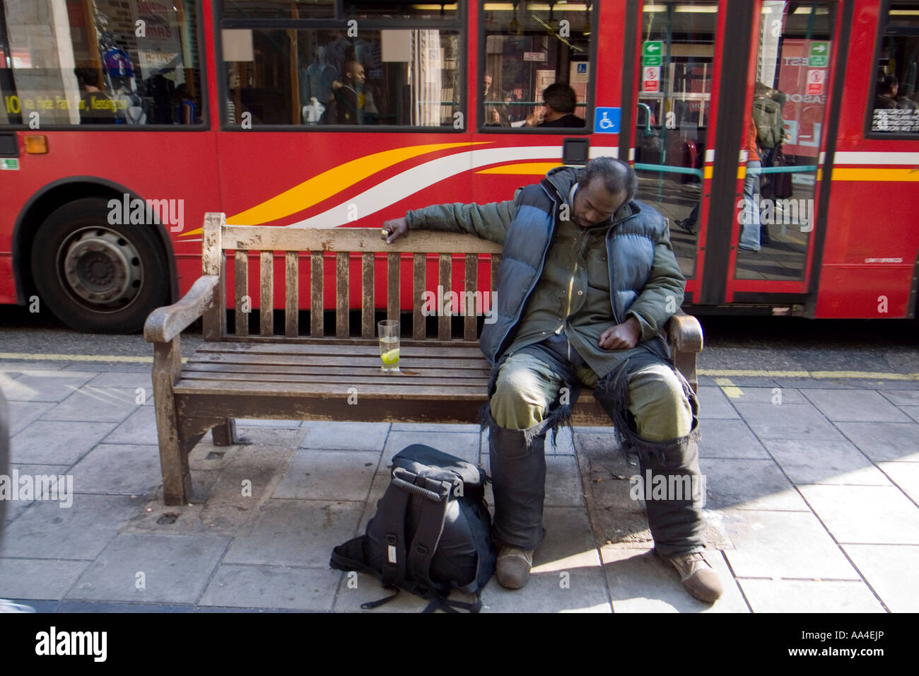 Obdachloser Einschlafen auf einer Bank mit einem Glas Gin Tonic auf seiner Seite, Oxford Street, London, UK Stockfoto