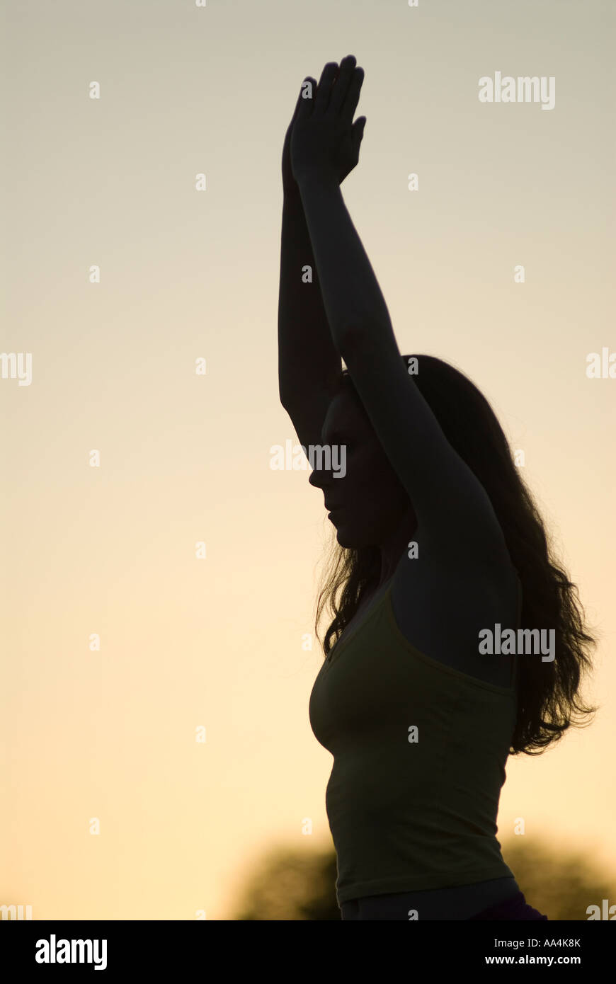 Silhouette einer jungen Frau, die beim Yoga bei Sonnenuntergang-Krieger 1 pose Stockfoto