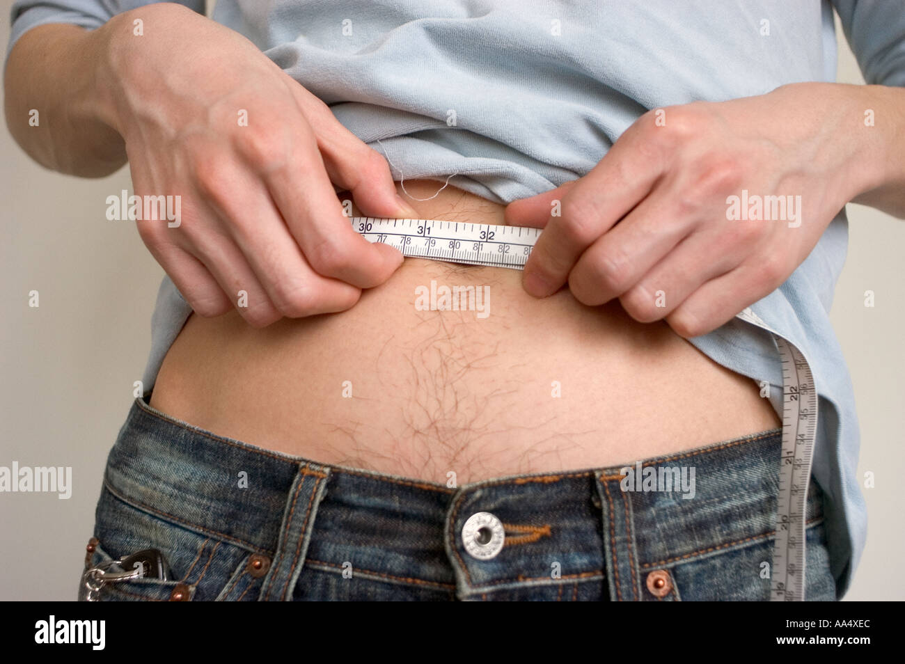 Young Asian Man, Messen seine Taille Band Gesundheit Gewicht Diät Konzept Körperbeherrschung Stockfoto