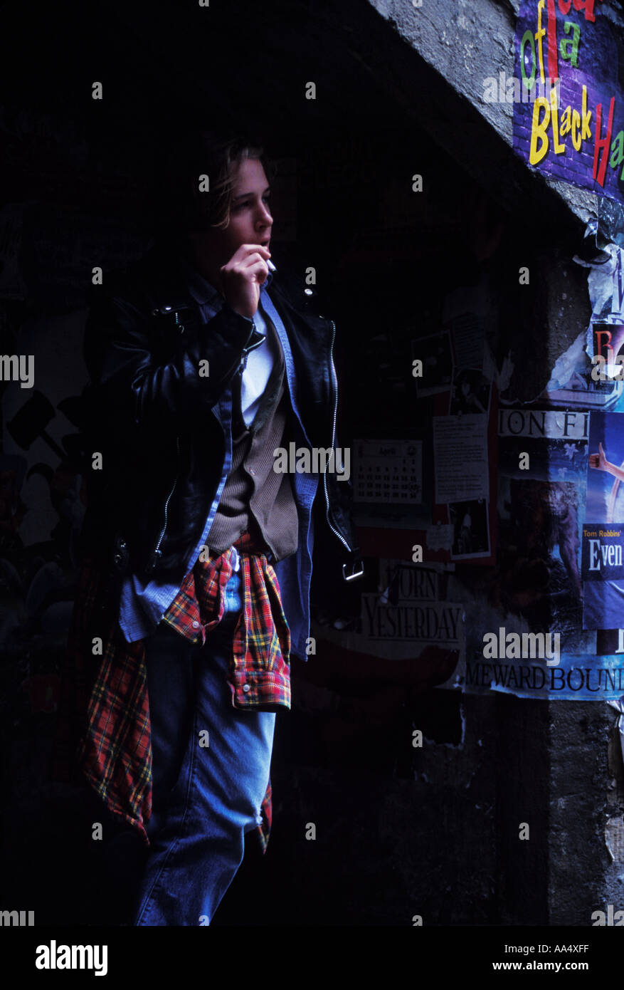 Eine Streetboy raucht eine Zigarette unter eine konkrete Treppe mit Plakaten geschmückt Stockfoto