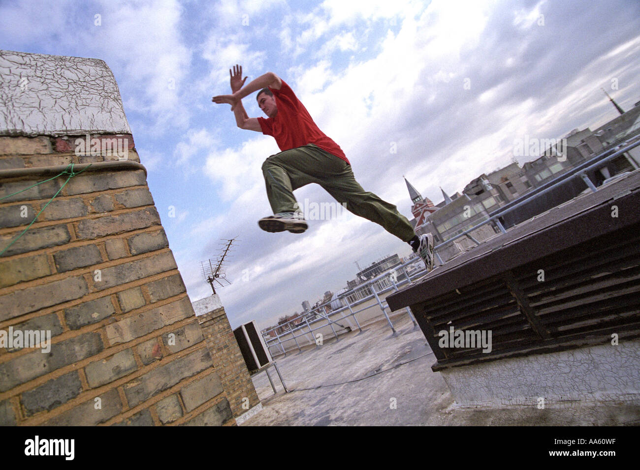 Ein Parkour-Freerunning-Athlet springt zwischen den Wänden auf einem Dach Stockfoto