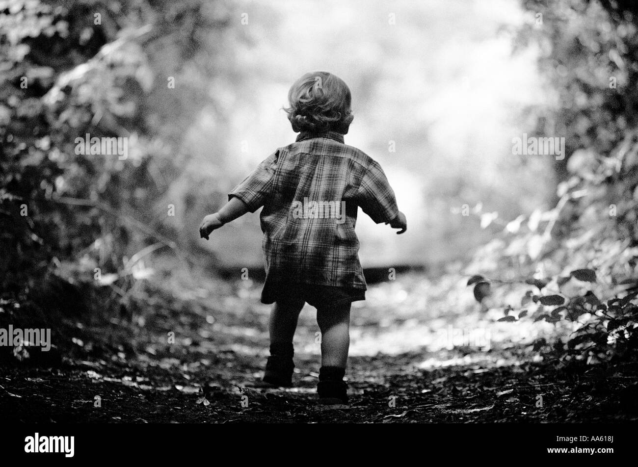 Kleiner Junge läuft Weg durch Wald Stockfoto