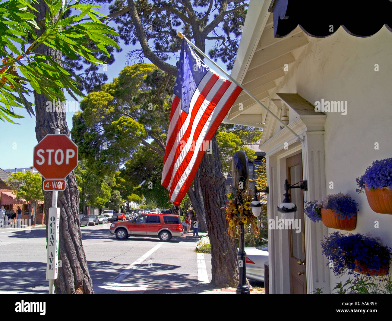 Carmel Street Scene Ocean Avenue mit amerikanischer Flagge stop-Schild und Allradantrieb Fahrzeug SUV auf Ocean Avenue Carmel Monterey County California USA Stockfoto