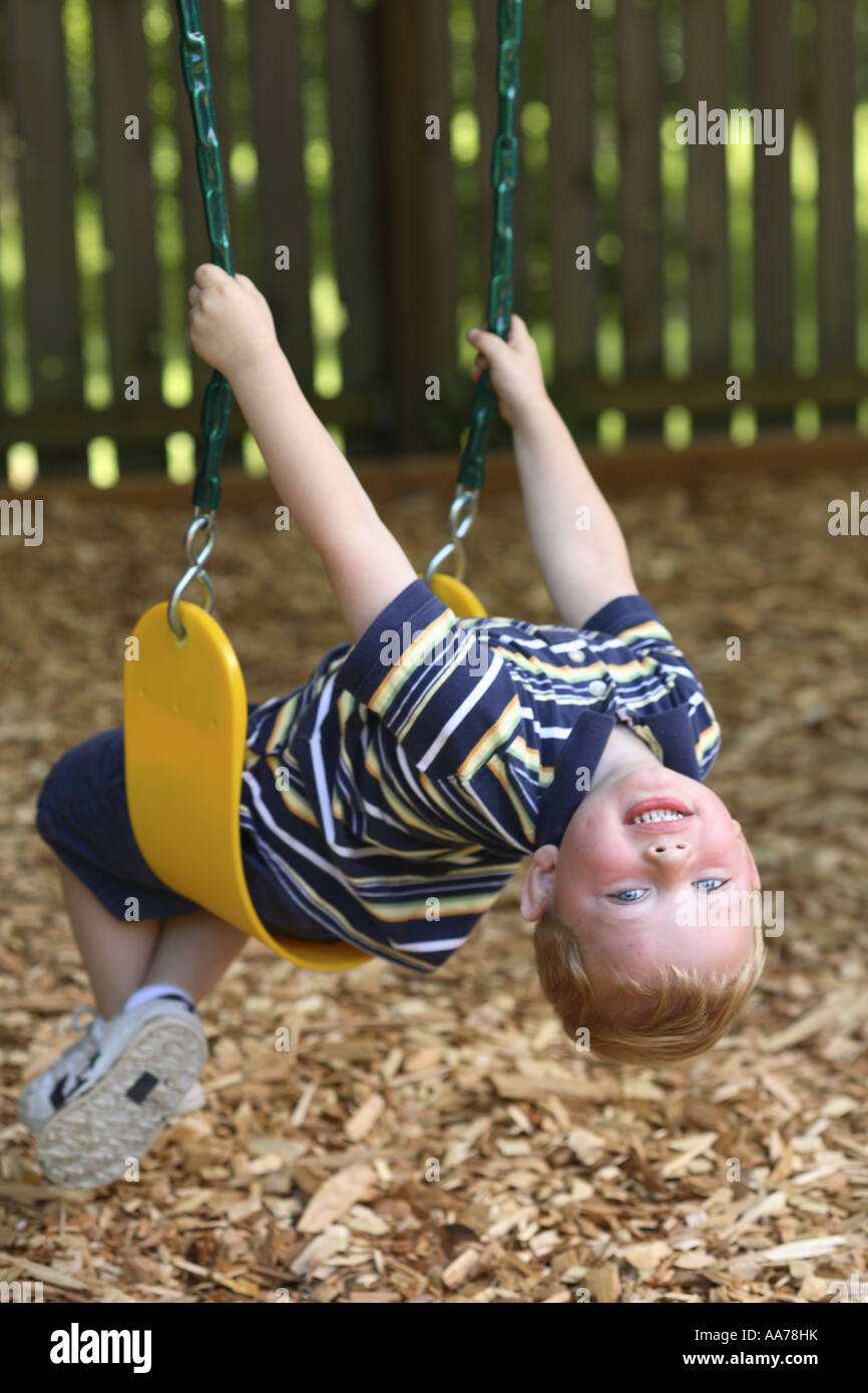 Zwei Jahre alter Junge auf Schaukel mit Kopf zurück Blick in die Kamera Stockfoto