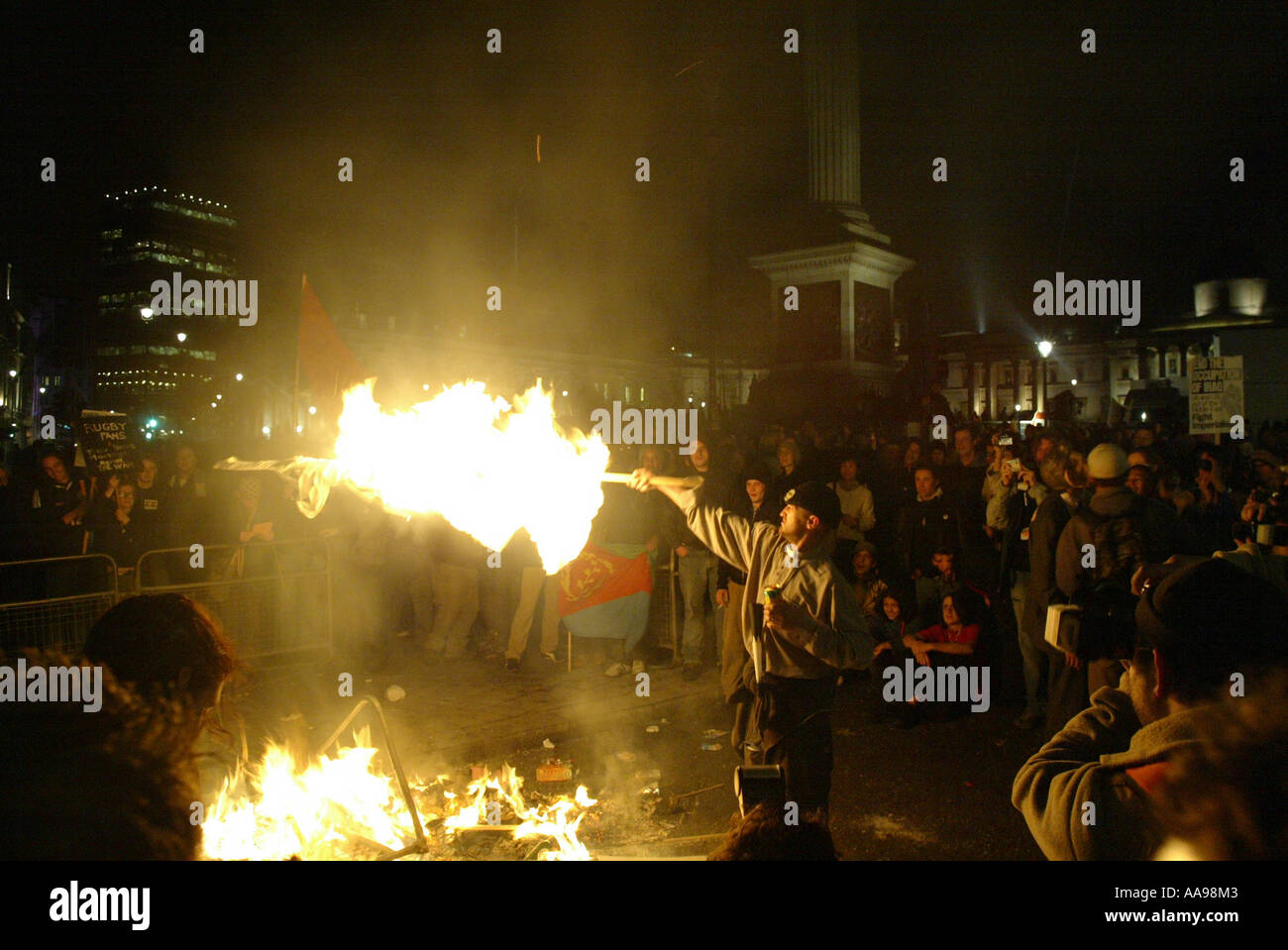 A ANTI-KRIEG PROTESTOR VERBRENNUNGEN, DIE EINE FLAGGE IN TRAFALGAR SQUARE IN LONDON AUF EINEN ANTI-GEORGE BUSH IM JAHR 2003 MÄRZ Stockfoto