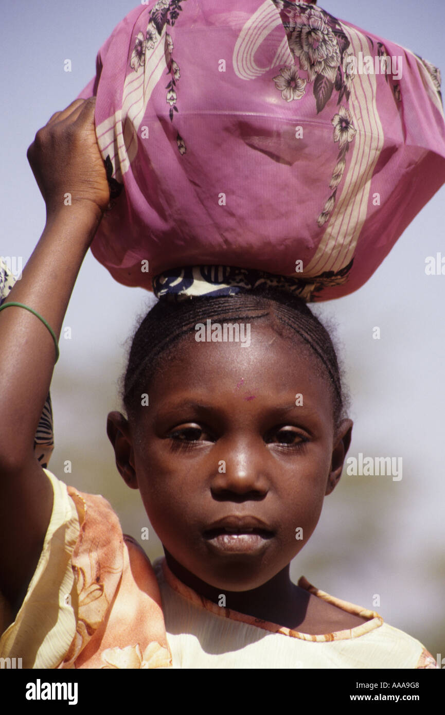 Niamey, Niger, Afrika. Mädchen tragen Bündel auf Kopf Stockfoto