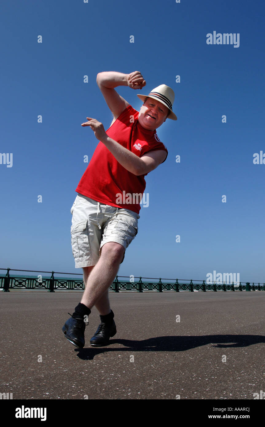 Ein übergewichtiger Mann mittleren Alters hart konzentrieren und dabei ungeschickt Tanz-Routine auf Brighton seafront Stockfoto