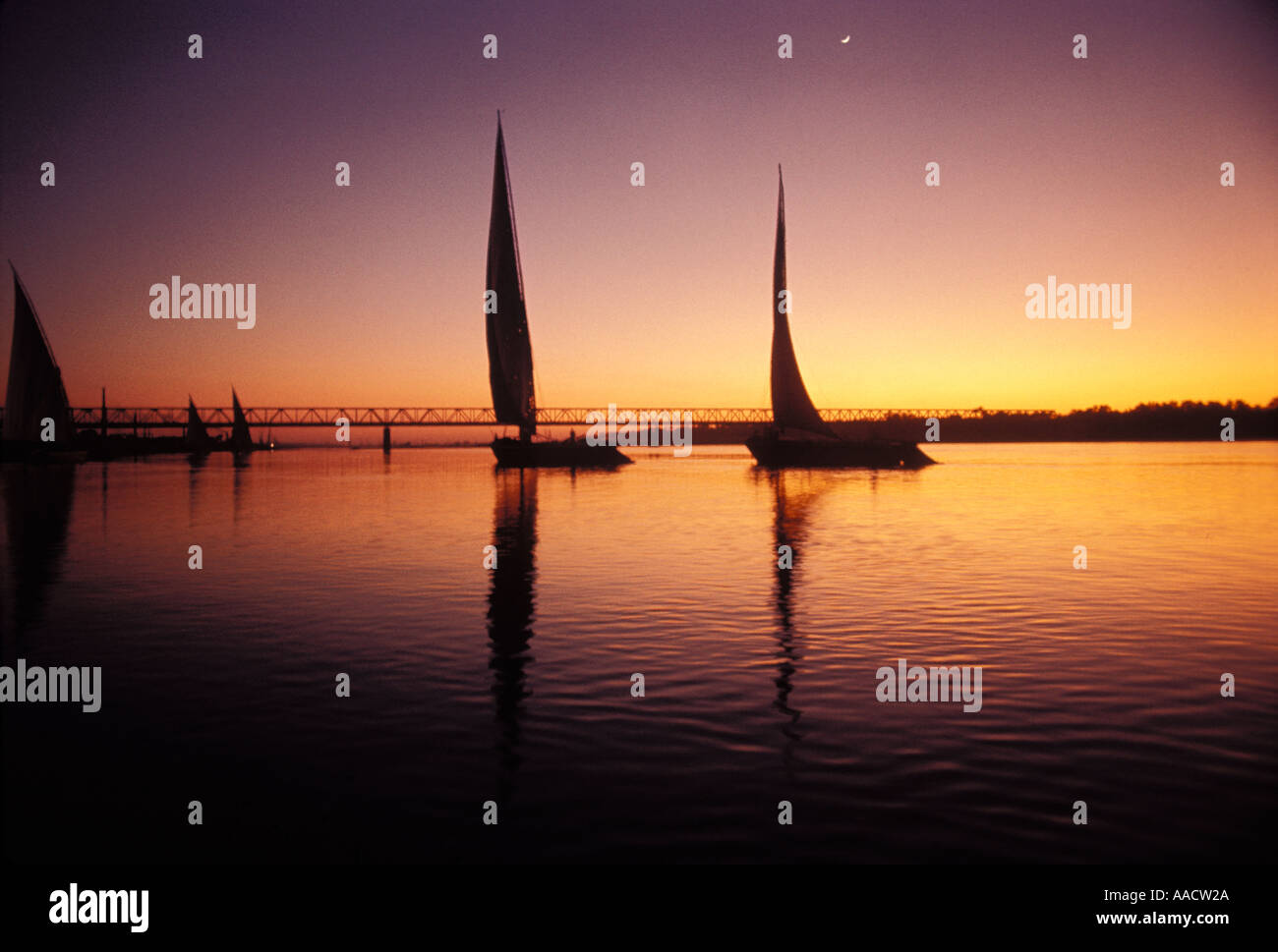Sonnenuntergang und Mond mit Silhouette und Reflexionen der Fischerboote auf dem Nil in Ägypten Stockfoto