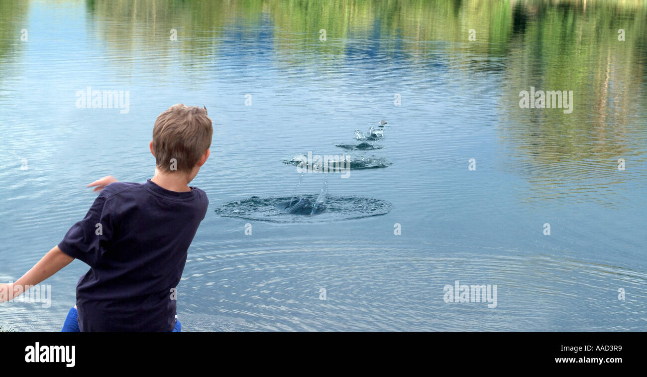 Junge spielt mit Steinen am Teich Stockfoto