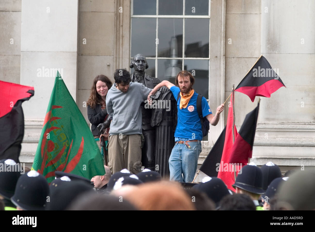 Demonstranten mit Anarchie Flagge auf Statue während der Mai-Demonstration. Trafalgar Square, London, England Stockfoto