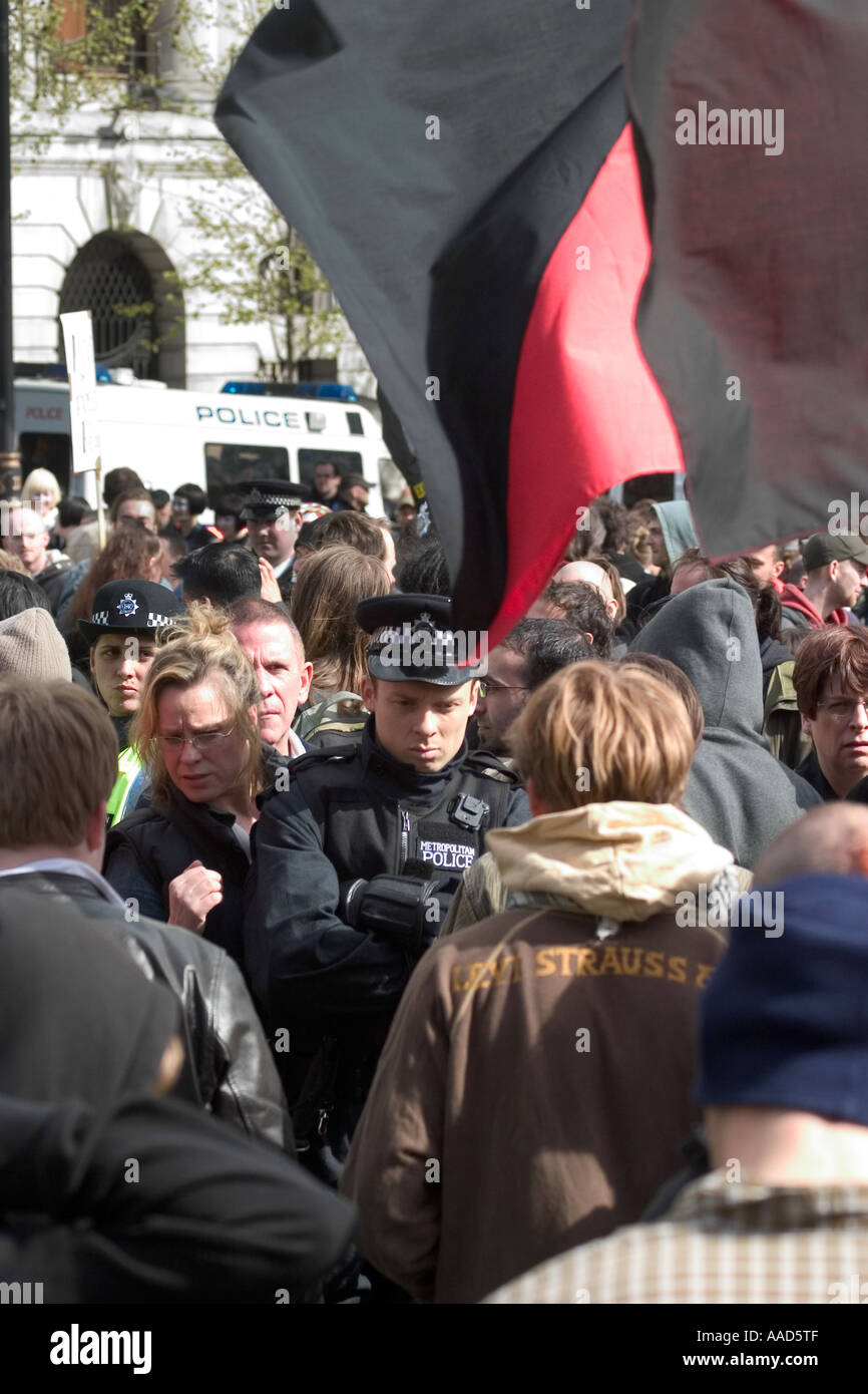 Grumpy suchen Polizisten, Zuschauer und anarchistischen Fahne während der Mai-Demonstration.  Trafalgar Square, London, England Stockfoto