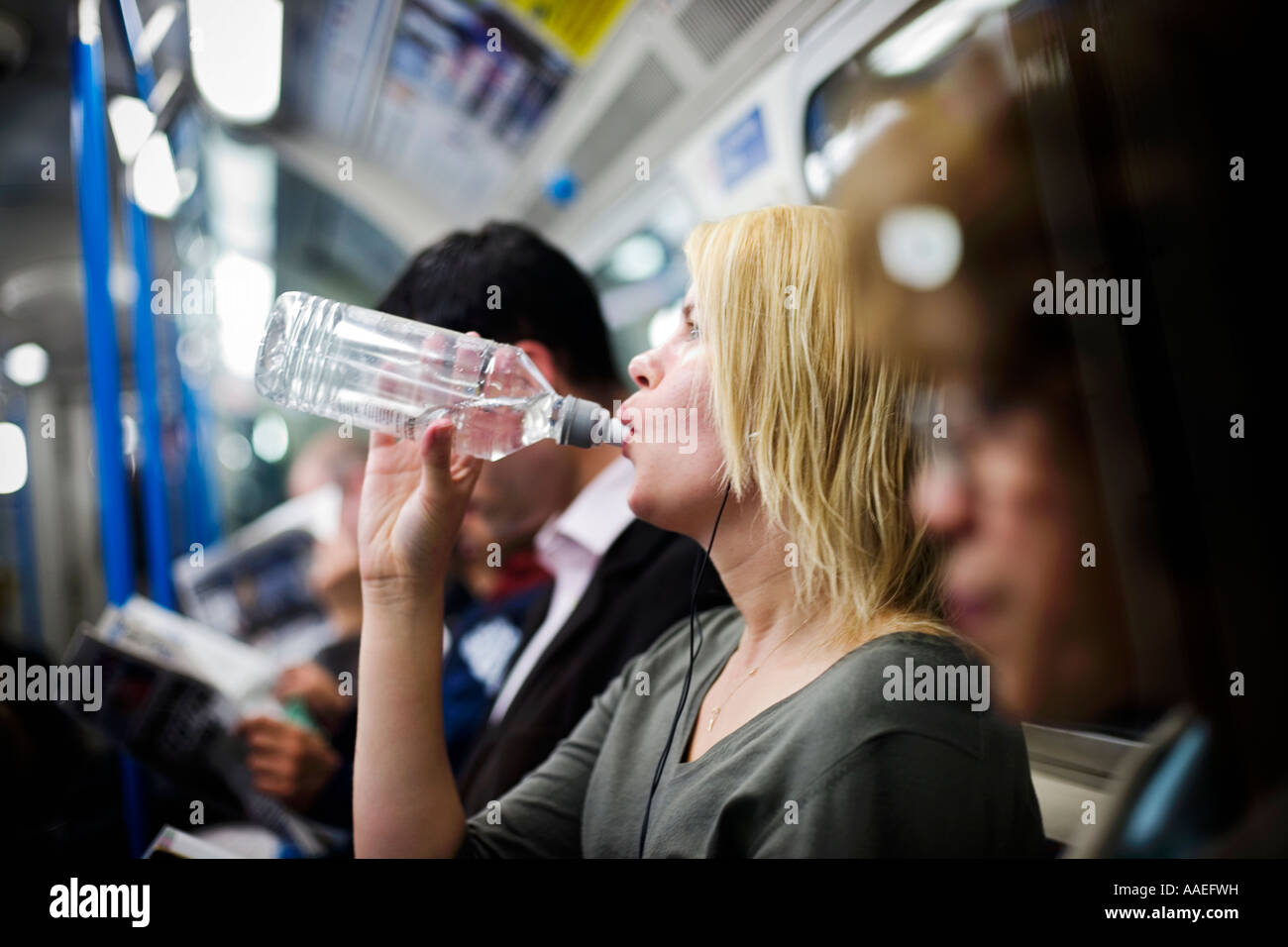 Frau auf u-Bahn nimmt einen Schluck Wasser während der schwülen Bedingungen Stockfoto