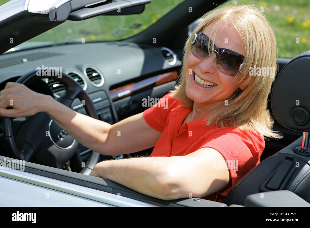 Eine ältere Frau Cabriolet Sportwagen mit Dach hinunter fahren Stockfoto