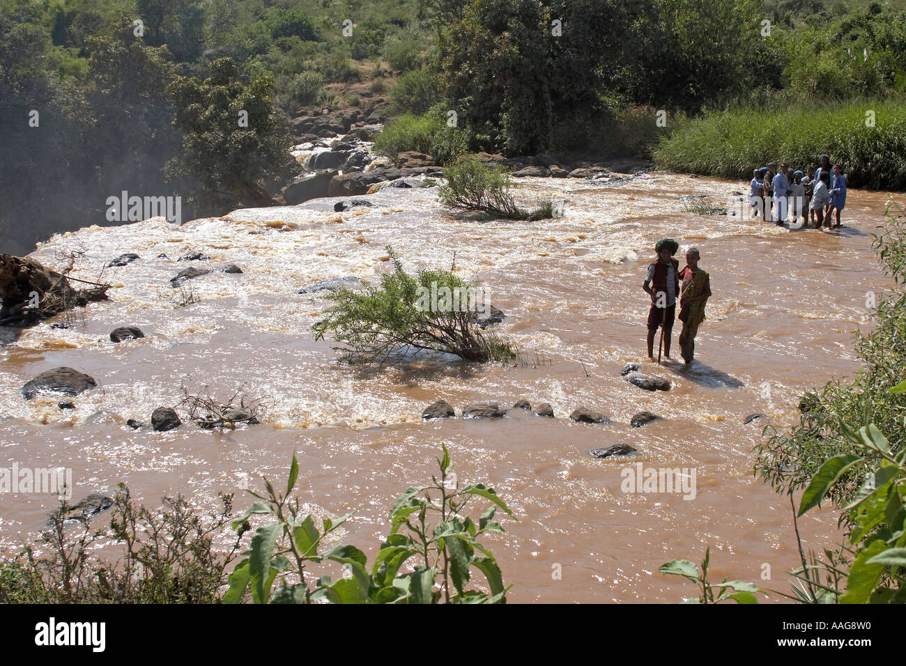 Menschen waten oder fording einen gefährlichen Fluss an der Spitze eines Wasserfalls in der Nähe von Kuch Äthiopien Afrika Stockfoto