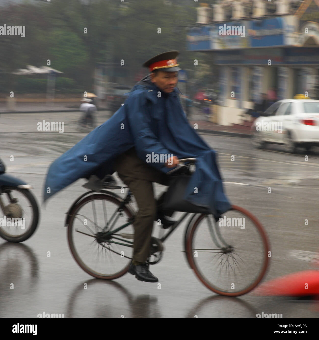 Nordöstlichen Vietnam Hanoi Old Quarter Polizist Reiten ein Fahrrad unter dem Regen mit Nylon Rundumschutz Stockfoto