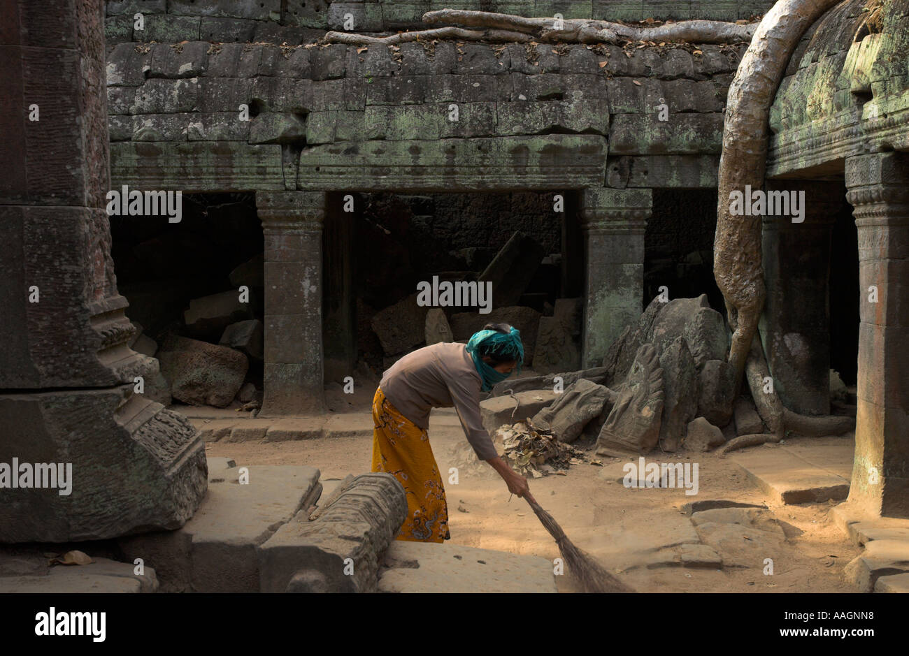 Kambodscha Siem Reap Provinz Tempeln von Angkor Archäologische park Ta Prohm Tempel Frau kehren Staub im Innenhof mit aufgewachsen Stockfoto