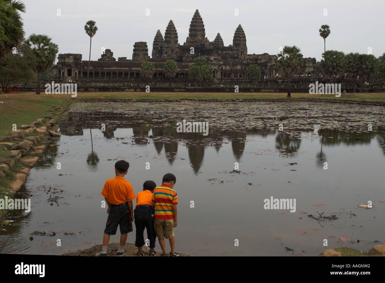 Kambodscha Siem Reap Provinz Tempeln von Angkor Archäologische park Kinder orange Hemd und spielen im Wasser-Teich mit einer Stockfoto